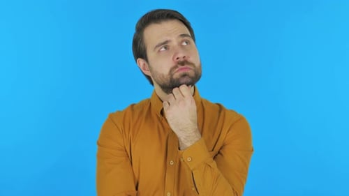Mann beim Brainstorming über eine neue Idee auf blauem Hintergrund, Portrait