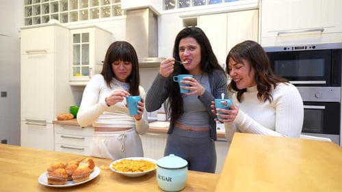 Friends Laughing and Chatting Over Muffins in Kitchen