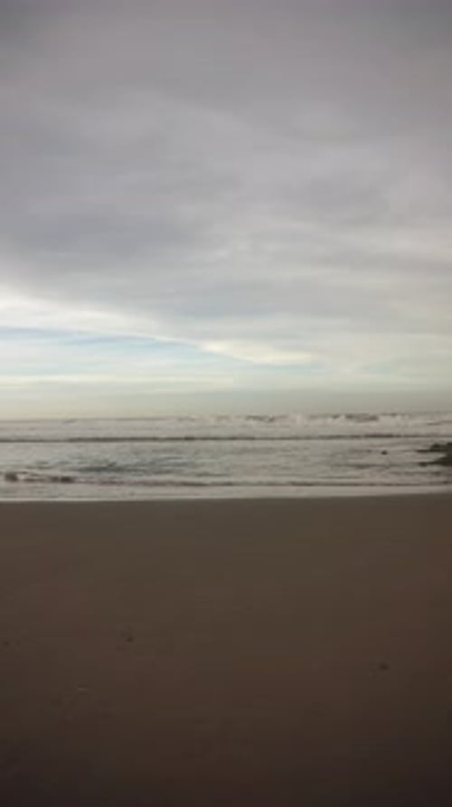 beautiful vertical video view of the sunrise on the beach with small waves, morning natural panorama