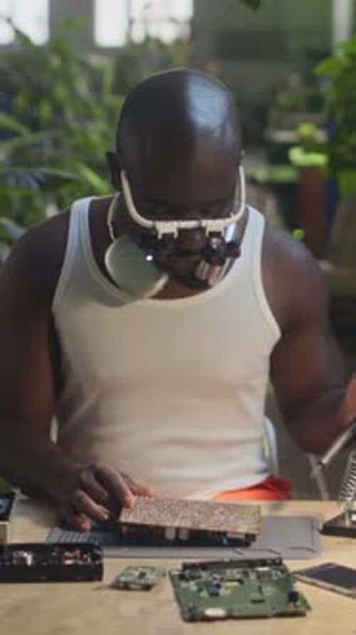Vertical of African American Male Technician Assembling Motherboard at Factory