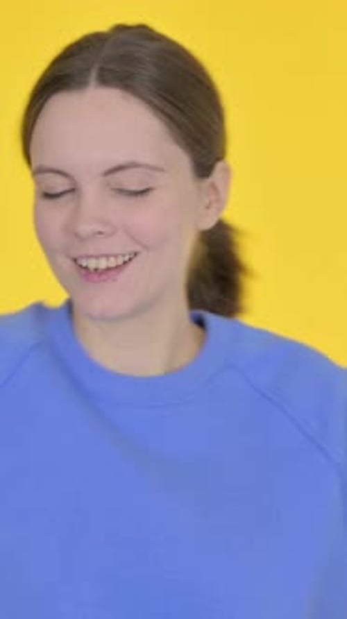 Young Woman in Blue Shirt Dancing on Yellow Background