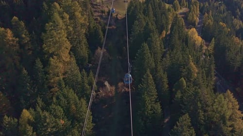 Mountain cable car ride under clear blue sky, drone perspective.