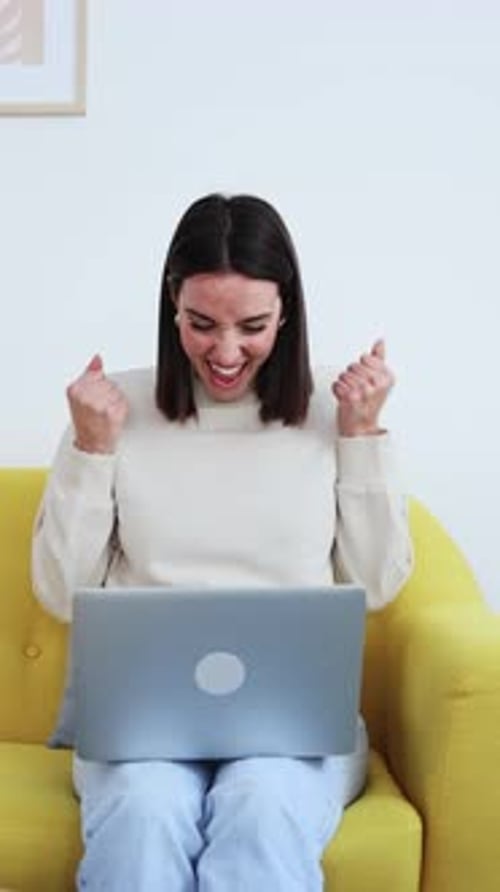 Woman Celebrating Success on Laptop at Home
