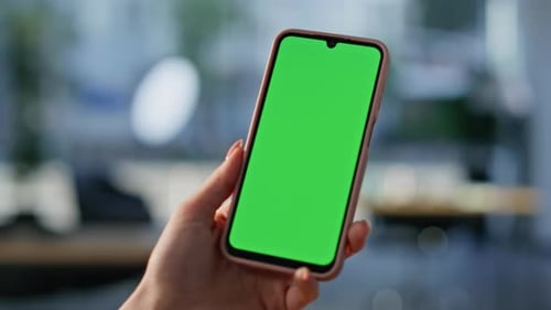 Woman Holds Smartphone with Green Screen in Office
