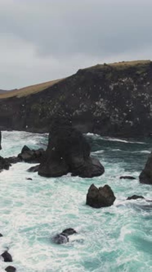 Rough atlantic ocean waves hitting the dramatic rocky shore of Valahnukamol