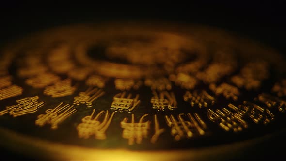 close up of Chinese ideogram characters on gold plate rotate on black ...