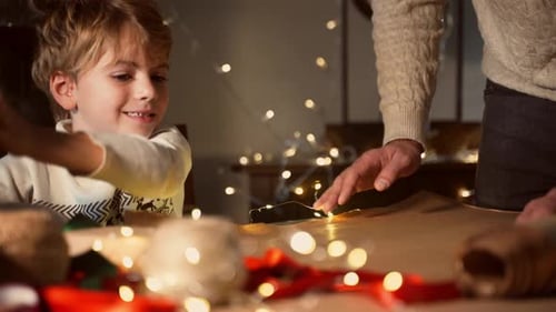 Boy and Adult Wrapping Christmas Gifts Together