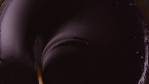Plan statique en gros plan, vu du dessus, montrant du chocolat très noir mélangé avec un bâton en bois