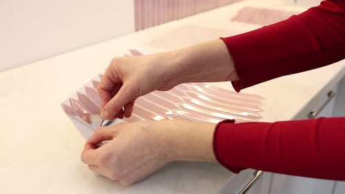 Hands Applying Light Red Tile Sticker to Wall
