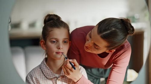 Mutter färbt die Lippen ihrer Tochter im Badezimmerspiegel, Nahaufnahme, Morgen-Make-up