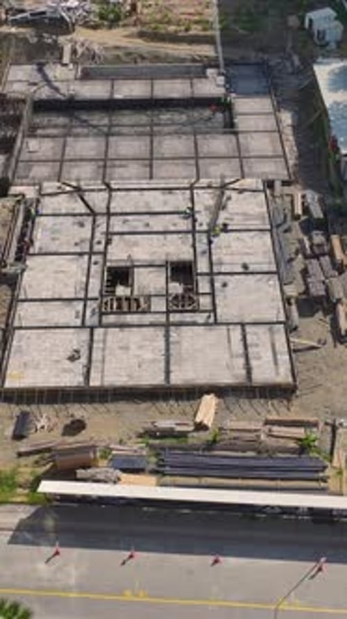 Vídeo vertical Los trabajadores colocan ladrillos y construyen paredes en una obra en construcción activa que avanza hacia