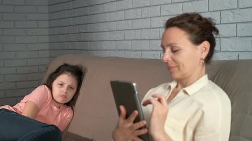 Mother Uses Tablet, Child Looks On