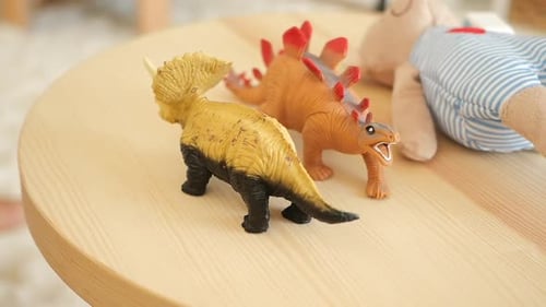 Child's Hand Picks Up Dinosaur Toy From Table