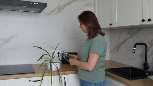 Woman Watering Indoor Plant in Modern Kitchen During Daytime
