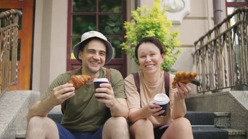 A Group of Happy Traveler Friends Wearing a Panama Hat and Carrying Backpacks Enjoy Delicious