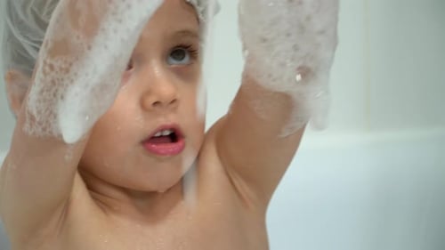 Girl Wearing Shower Cap Playing in Bath Tub