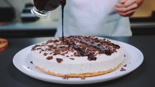 Chocolate Sauce Being Drizzled Over Cheesecake Dessert
