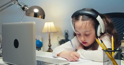 Schoolgirl Girl in Headphones Studies at Home and Does School Homework