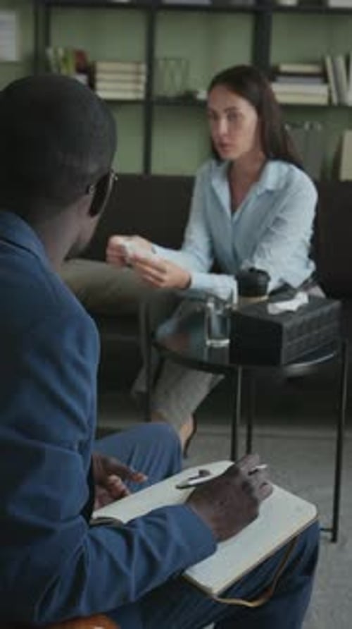 Male Counsellor Writing in Notebook Giving Consultation to Upset Woman