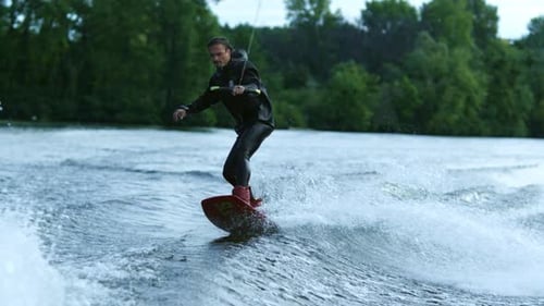 Athlete Doing Tricks on Wakeboard. Young Man Wakeboarding on River Wave. Wake