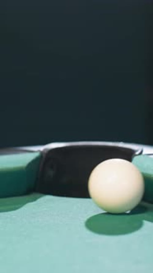 Black Billiard Ball Rolling Toward Pool Pocket After White Cue Ball Strike