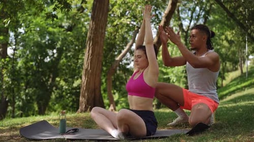 Woman Practicing Yoga with Instructor in Park
