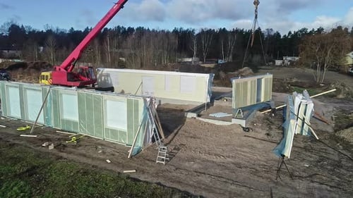 Modular home assembly on construction site with crane
