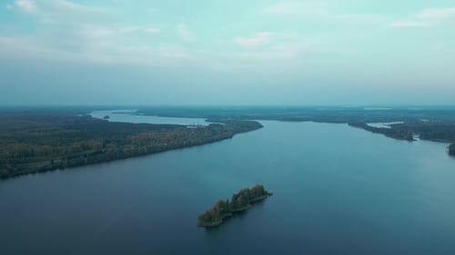the Camera Flies Over a Wide River in the Middle of the Forest During Sunrise