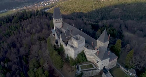 Drone Shot of a Castle on a Mountain revealing a beautiful Landscape, flying backward while tilting