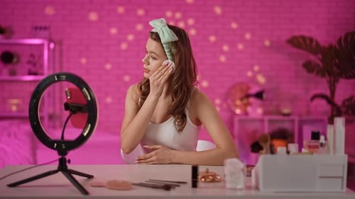 Young Woman Applying Skincare Products in Bright Pink Room