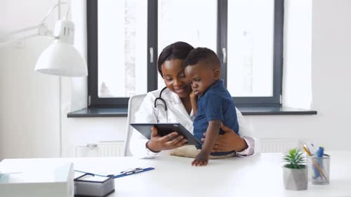 Friendly Doctor Showing Toddler Tablet at Appointment