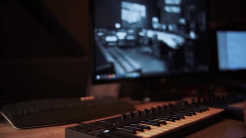 Panoramaaufnahme eines Musikstudios, Computerbildschirm, Tastatur, Klavier, Ringlicht, DJ-Kopfhörer, Subwoofer,