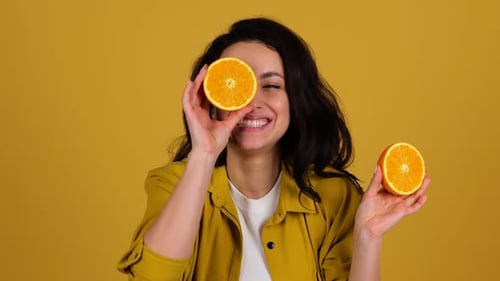 Smiling Woman with Oranges Against Yellow Background