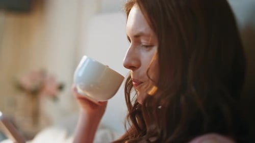 Woman Drinking Coffee and Using Cellphone Indoors