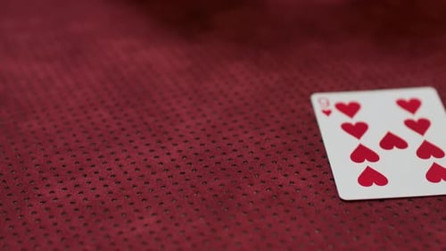 Playing cards being placed on a red surface