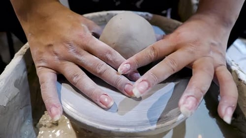 overhead close view of an African American hands spinning clay and setting the wet mold on the wheel