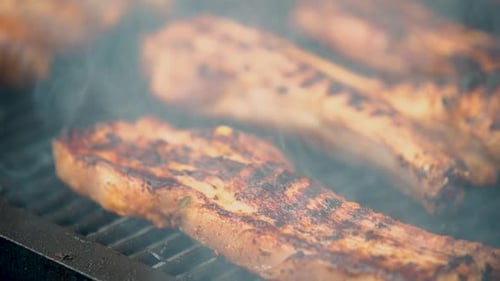 Grilling juicy pork ribs in a backyard barbecue setting on a sunny afternoon in summer.