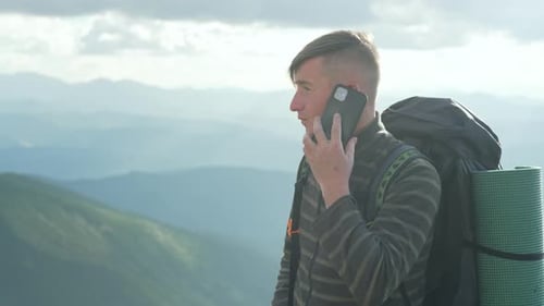 A Guy with a Phone While Hiking in the Mountains Makes a Call