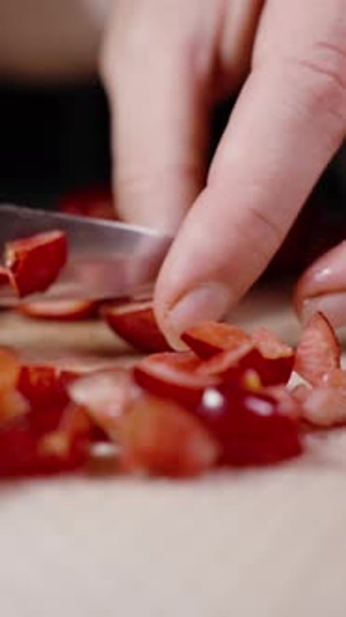 Vertical video. A Woman Slices Cherries On A Soft Cutting Mat. Slow Motion Macro.