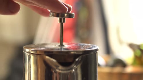 Man presses a stainless steel french press