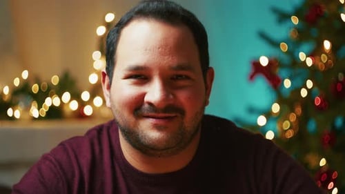 El hombre sonríe feliz frente al árbol de Navidad en vacaciones