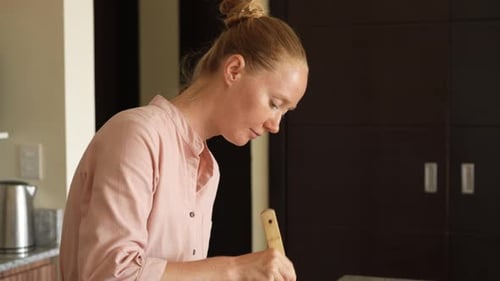 Woman Preparing Food in Kitchen with Wooden Spoon