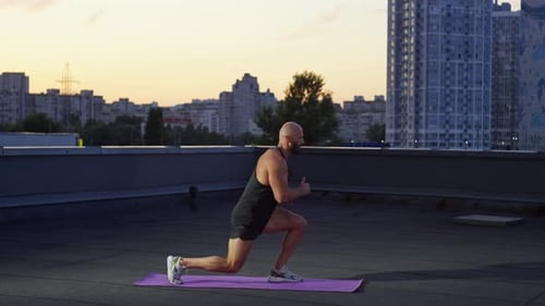 Muscular Man Exercising on Rooftop at Sunrise