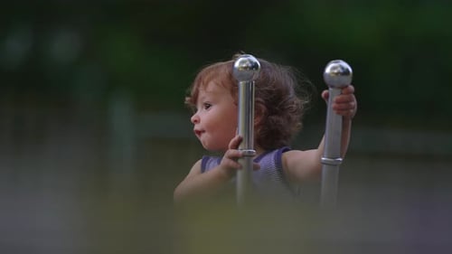 Toddler gripping metal handles of playground digger with curious expression capturing engagement