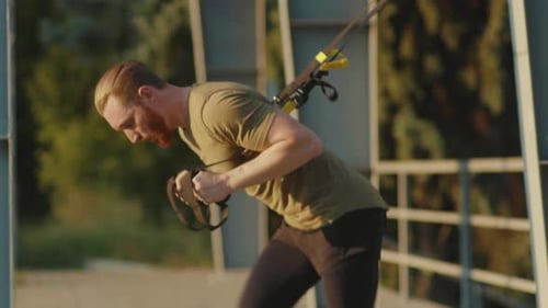 Close Up Young Strong Man Working Out with Trx Fitness Rope Body Exercises at Stadium Muscular