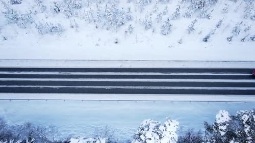 Winter road with a red car driving horizontal