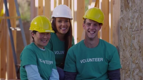 Volunteers Smiling and Waving at Construction Site