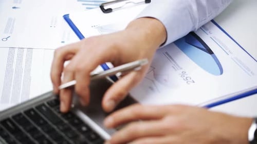 Businessman hands typing on laptop analyzing financial data in office