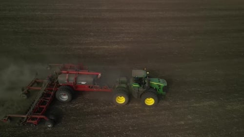 Green tractor seeding wheat on the field