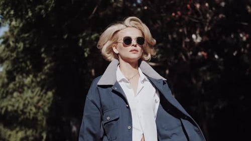 A Beautiful Blonde Girl in a Blue Coat is Walking Down the Street Autumn Fashion